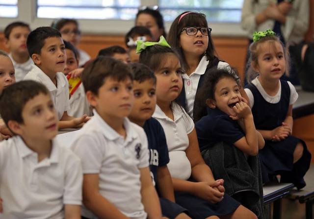 Schoolchildren sitting on the floor watching with interest