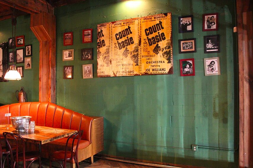A corner with an orange leather booth and a green wall of framed Count Basie posters