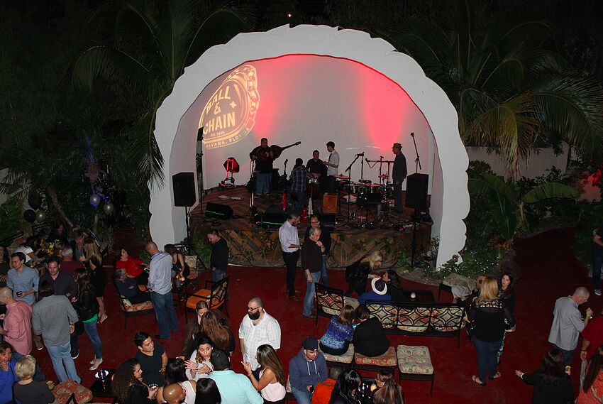 A crowd on a patio at night in front of a band on Ball & Chain's pineapple-shaped stage