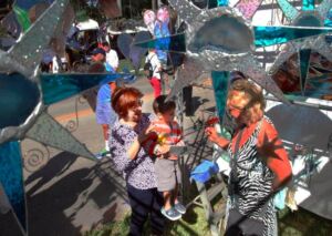 Visitors looking at a large metal sculpture of stars and spirals at an outdoor art festival