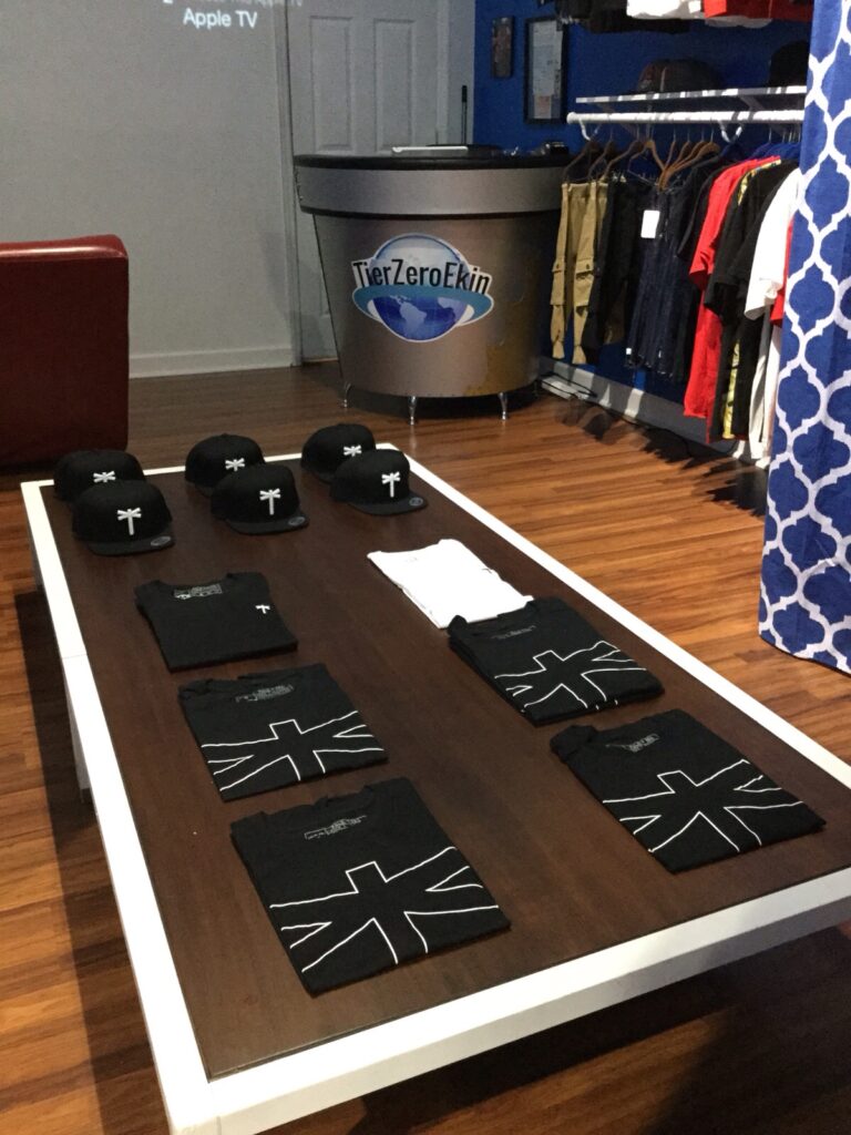 Black Palm Era T-shirts and caps laid out on a display table in a shop