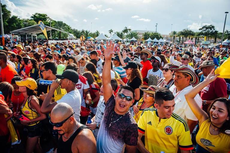 A crowd in Colombia football shirts cheering at an outdoor festival
