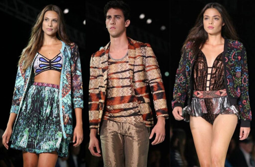 Three models, two women and a man, in printed and metallic resort wear on a runway