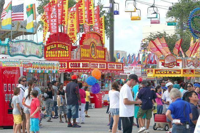 Crowds walking among colourful food stands and rides at the Youth Fair