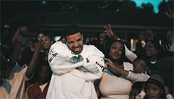 Drake in a white top dancing among a crowd at night