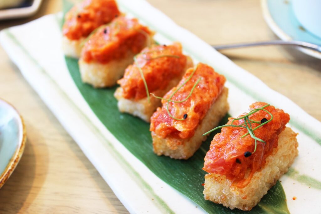 Small squares of crispy rice topped with spicy tuna, on a banana leaf