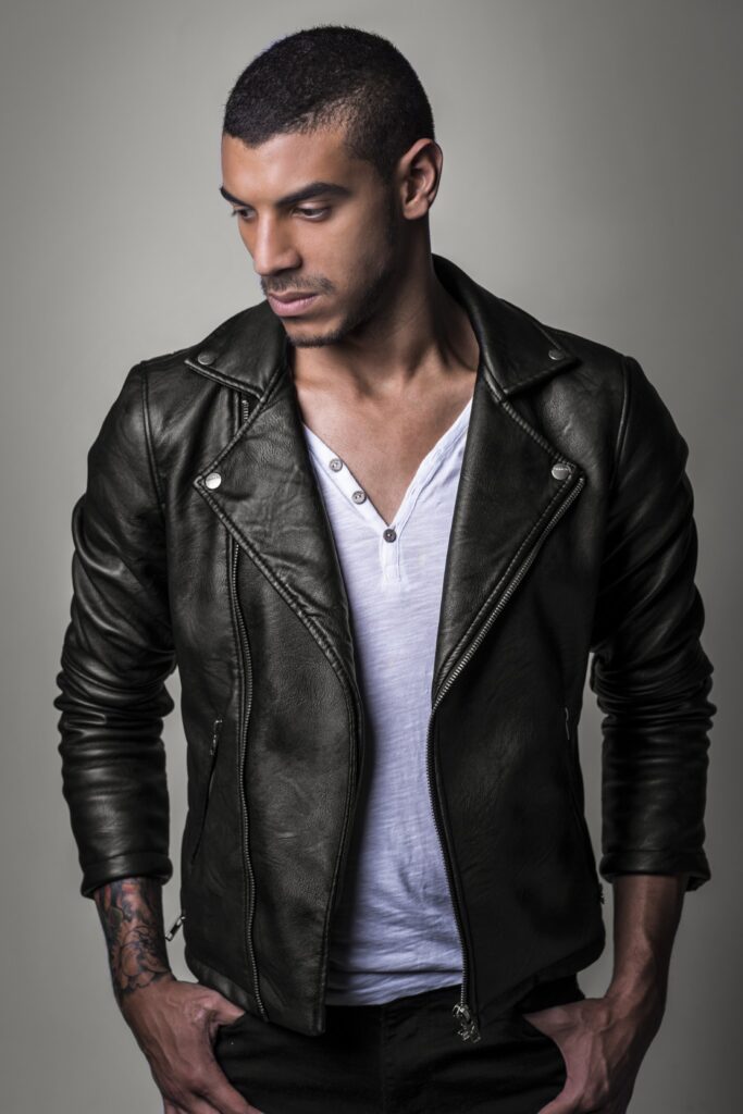 Manuel Medrano in a black leather jacket over a white T-shirt, looking down