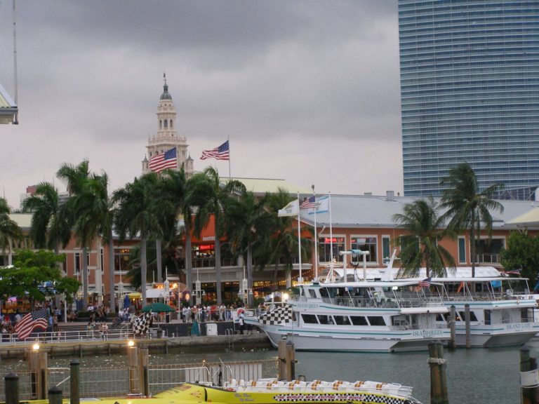 Bayside Marketplace's clock tower and a white tour boat in the harbour, a tower block behind
