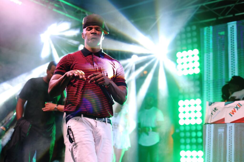 A man in a red polo shirt performing on a stage under green and white lights