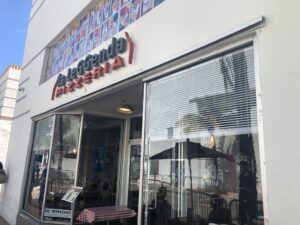 The front of La Leggenda Pizzeria, a white building with a red sign