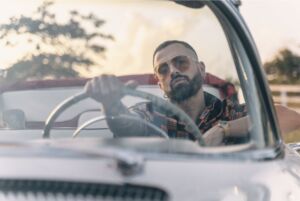 Mike Bahía in sunglasses at the wheel of a white vintage convertible