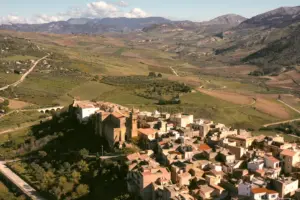 An Italian hill town of stone houses seen from above, with farmland and hills behind