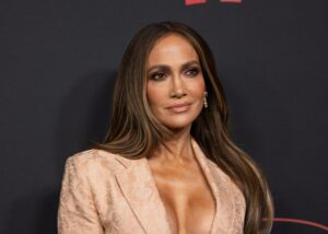 Jennifer Lopez on a red carpet in a blush-pink blazer, hair loose