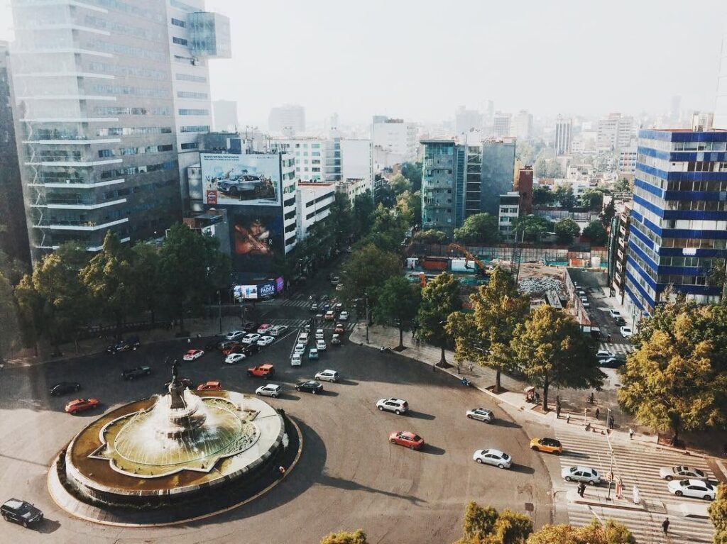 An aerial view of the Diana Cazadora roundabout in Mexico City, traffic circling the fountain, the city’s towers stretching out behind.